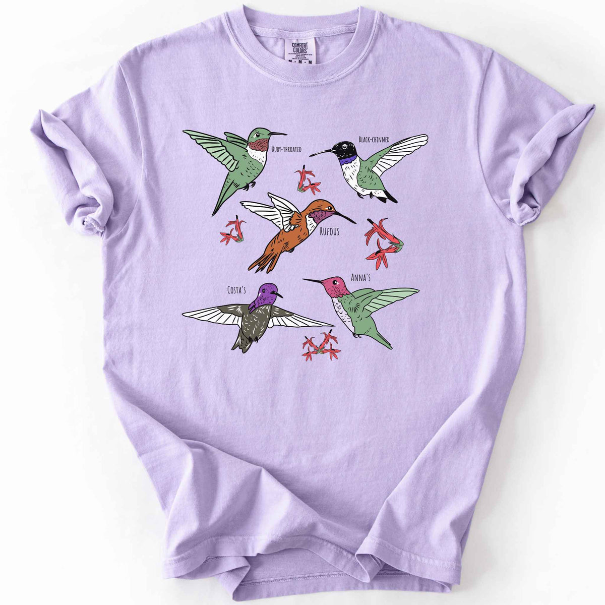 Orchid "hummingbirds" t-shirt on Comfort Colors tee, featuring five illustrated hummingbird species including Ruby Throated, Rufous, and Anna's, each labeled and shown among red flowers. Birdwatcher and hummingbird lover gift shirt for wildlife and nature enthusiasts.