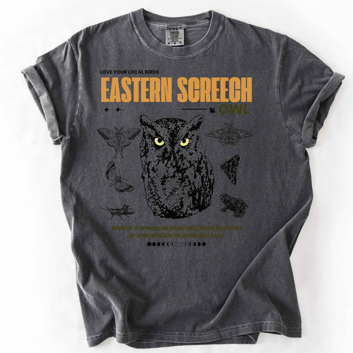 Pepper "Love Your Local Birds, Eastern Screech Owl" t-shirt on Comfort Colors tee, featuring a detailed owl portrait surrounded by moths, a frog, and a grasshopper with orange lettering and educational text. Birdwatcher and owl lover gift shirt for wildlife and nature enthusiasts.