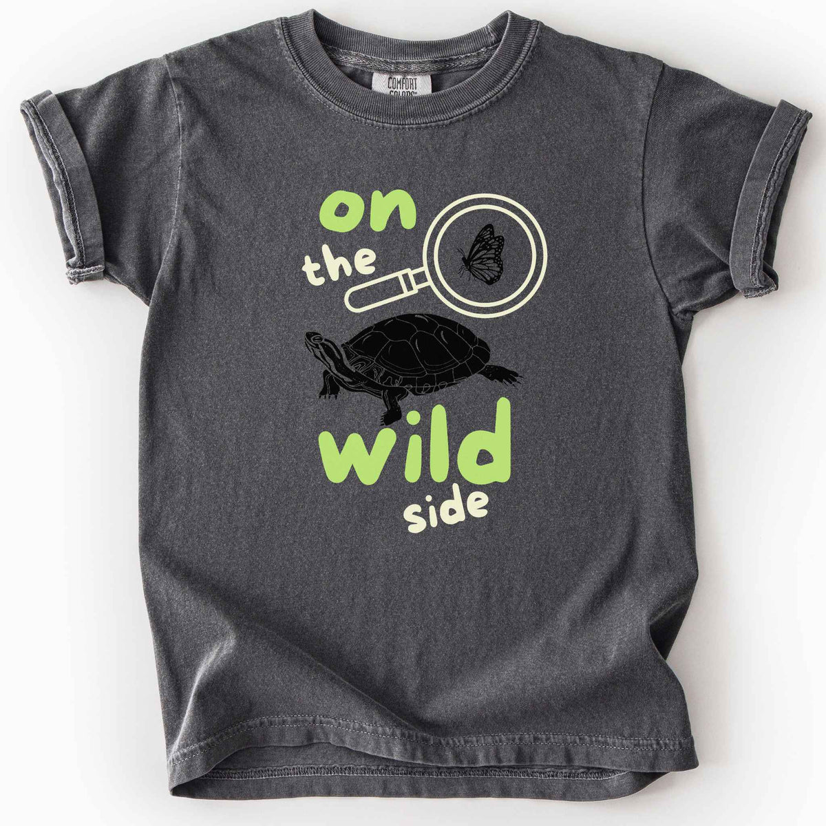 Pepper "On the wild side" kids t-shirt on Comfort Colors tee featuring a butterfly in a magnifying glass and painted turtle graphic with bold and playful text. Nature lover kids shirt for wildlife and exploration enthusiasts. 