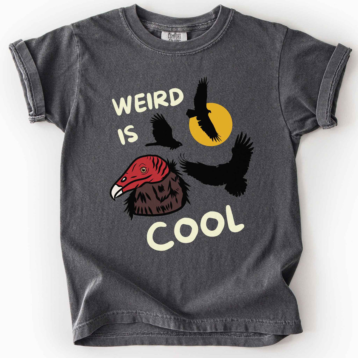 Pepper "Weird is cool" kids t-shirt on comfort colors tee featuring turkey vulture silhouettes and a hand-drawn profile graphic with bold white playful text. Gift for little beginning birders and wildlife enthusiasts. 