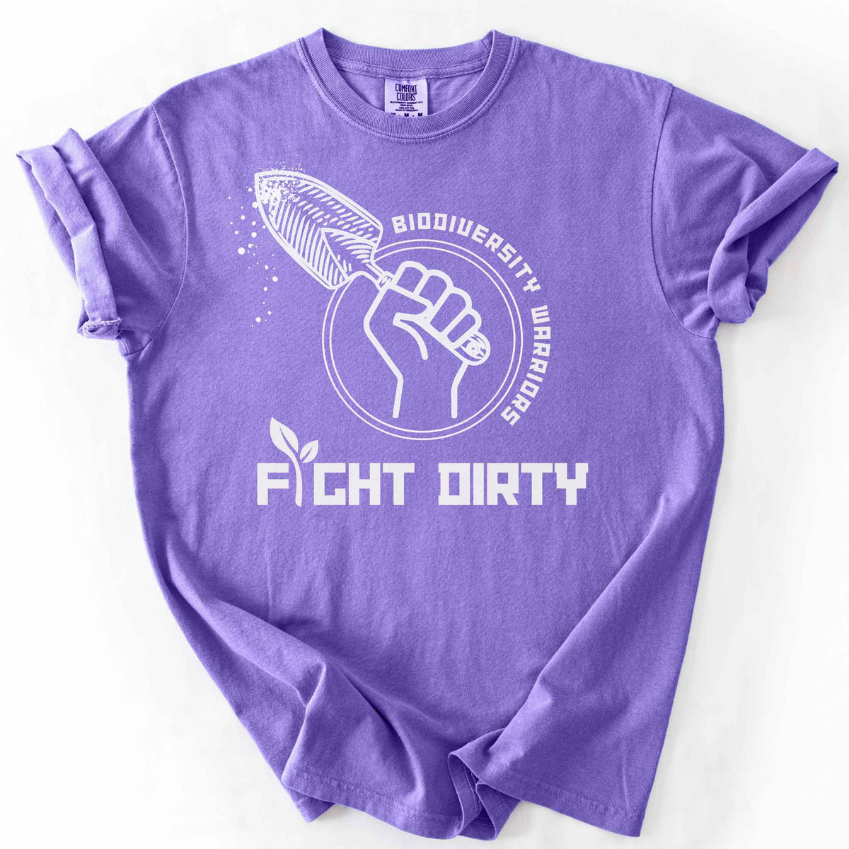 Violet "Biodiversity Warriors, Fight Dirty" t-shirt on Comfort Colors tee, featuring a raised fist gripping a garden trowel in a circular badge design. Gardener and conservation lover gift shirt for native plant and biodiversity enthusiasts.