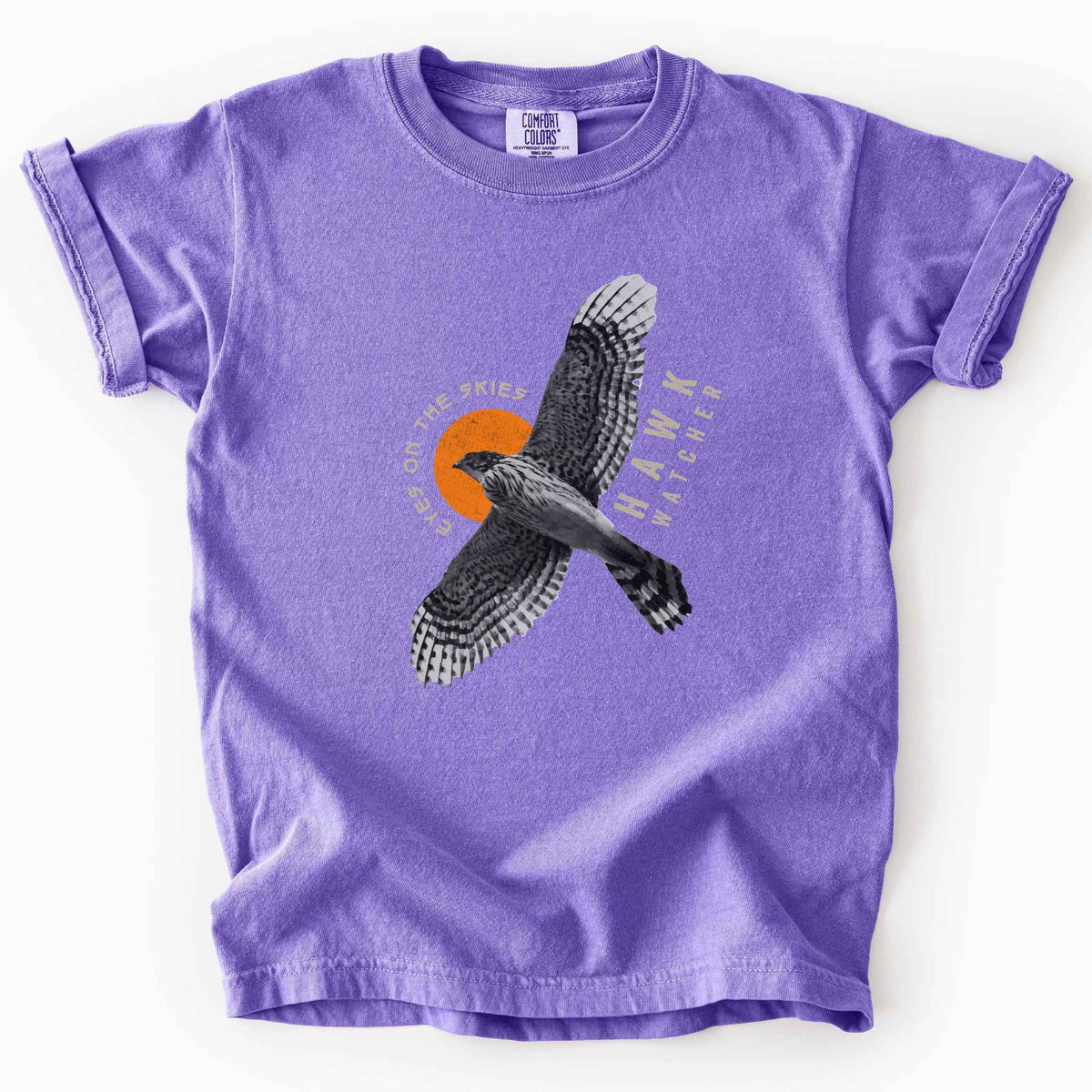Violet "Hawk Watcher, Eyes on the Skies" t-shirt on Comfort Colors tee, featuring a flying hawk graphic with spread wings against an orange sun design- birdwatching and raptor lover gift shirt for bird enthusiasts.