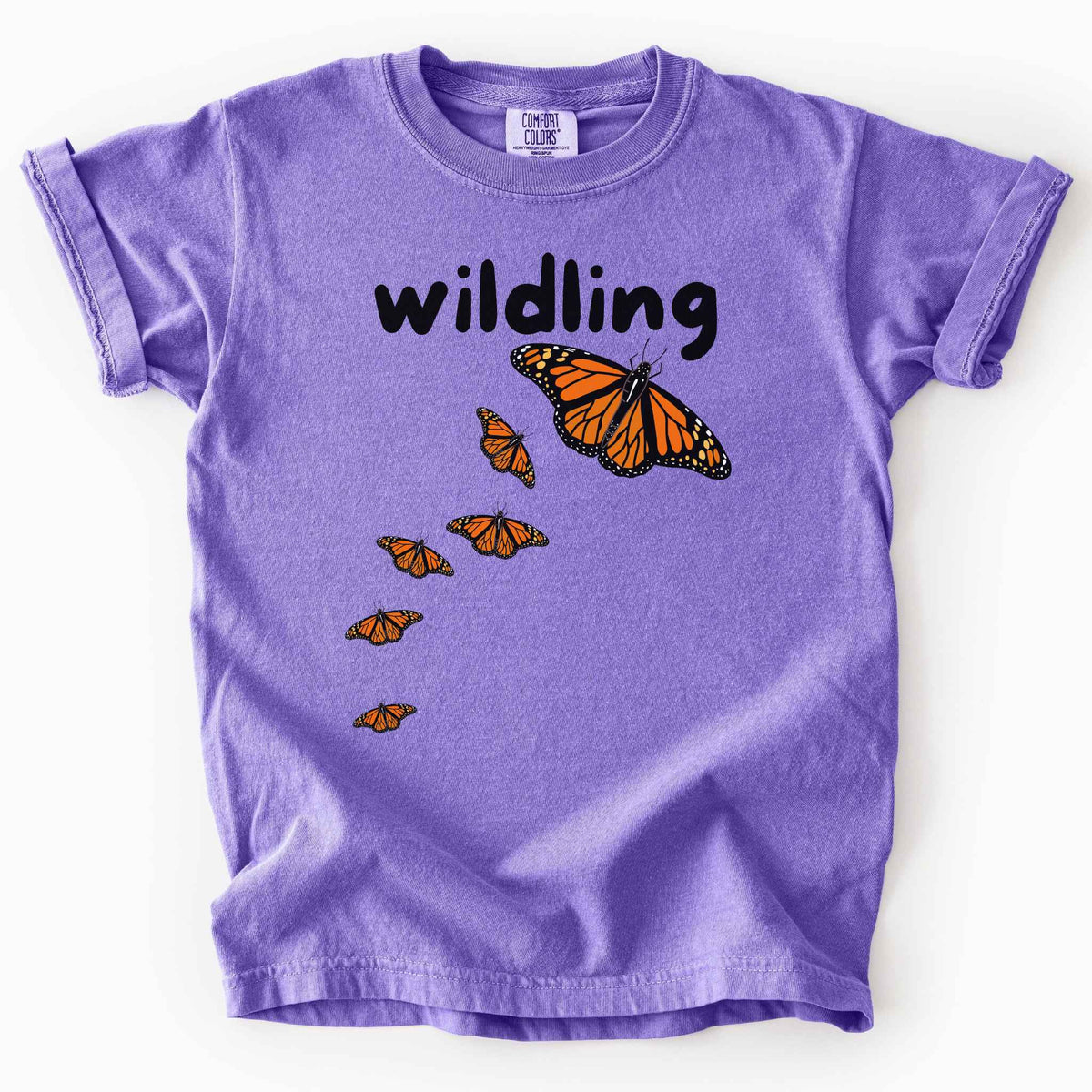 Violet "Wildling" kids t-shirt on Comfort Colors Tee featuring six Monarch butterflies in an upward ascending pattern and bold black text. Nature inspired gift for kids and butterfly enthusiasts. 