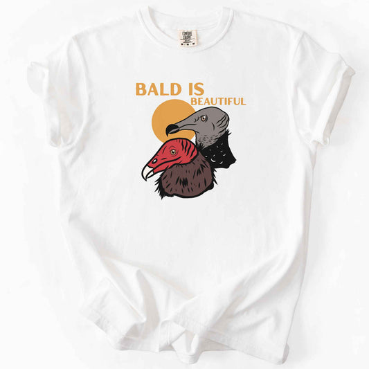 White "Bald Is Beautiful" t-shirt on Comfort Colors tee, featuring illustrated turkey vulture and black vulture heads with orange retro sun and orange lettering. Funny birdwatcher gift shirt for vulture and scavenger lovers.
