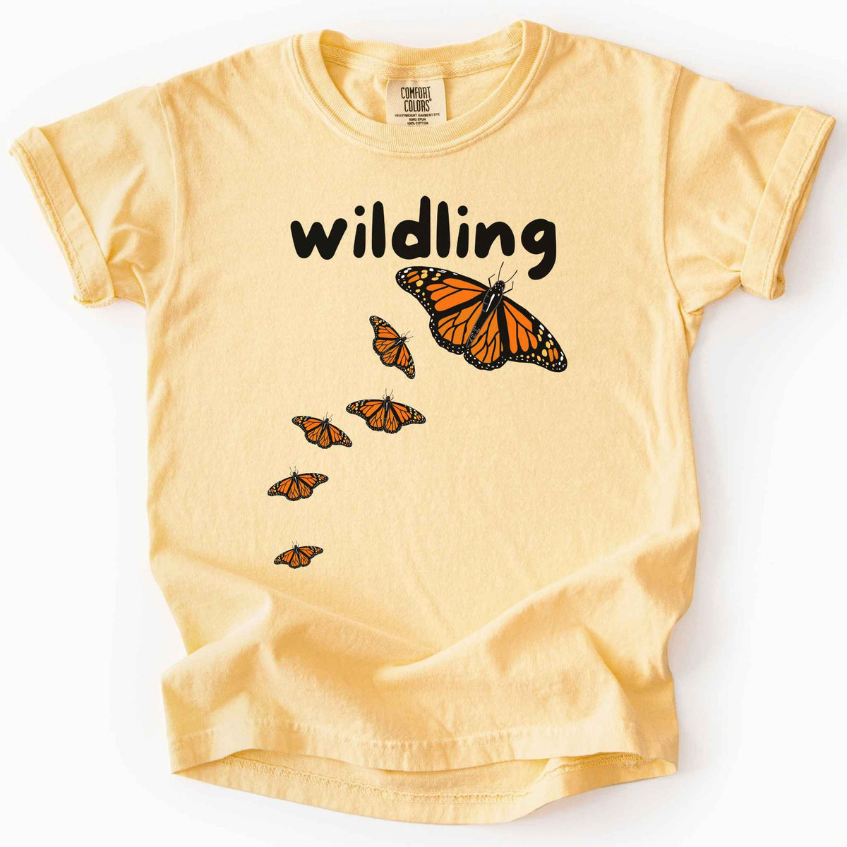 butter "Wildling" kids t-shirt on Comfort Colors Tee featuring six Monarch butterflies in an upward ascending pattern and bold black text. Nature inspired gift for kids and butterfly enthusiasts. 